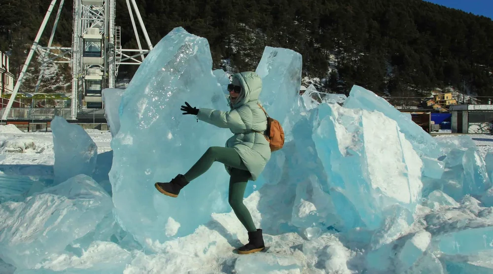 Tourist posing with large blue ice formations on Lake Baikal in Listvyanka
