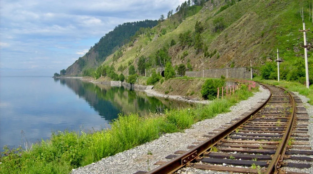 Scenic view of the Circum-Baikal Railway tracks along the shore of Lake Baikal with mountains in the background
