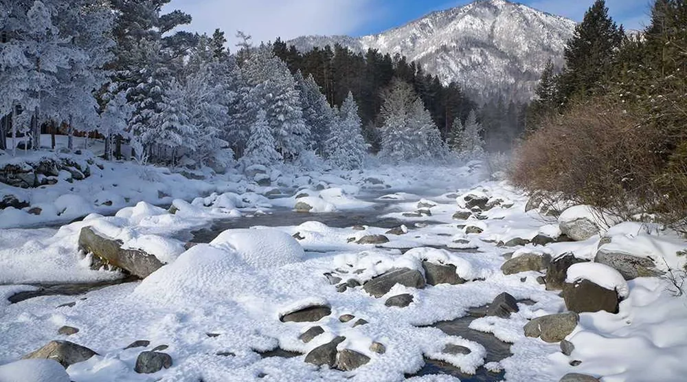 Snowy river landscape in Tunka Valley near Arshan with mountains and pine trees