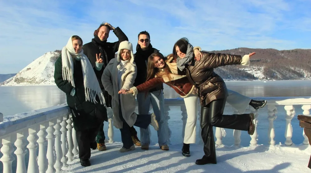 Group of happy tourists posing together during a winter tour in Listvyanka near Lake Baikal