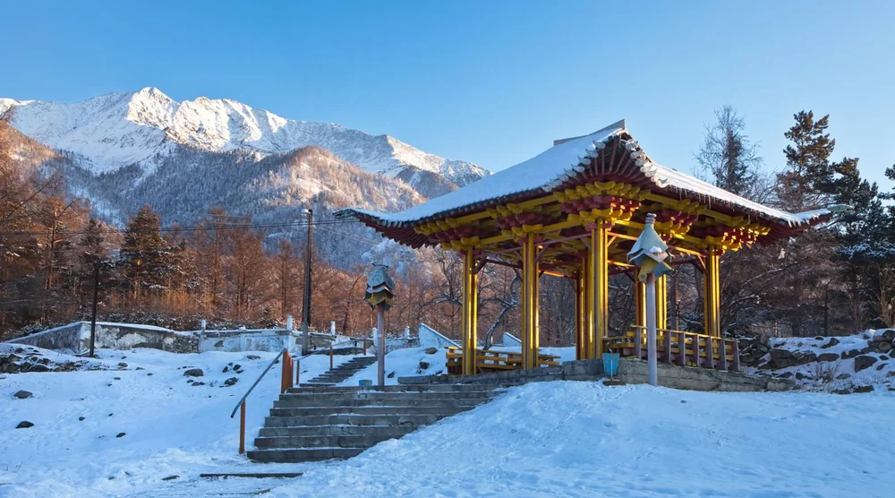 Traditional Buddhist pavilion with snow-covered roof in Arshan Tunka Valley mountains