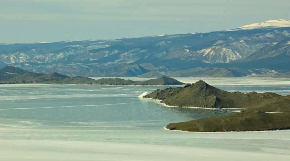 Frozen landscape of Lake Baikal with snow-covered mountains and ice formations on Olkhon Island