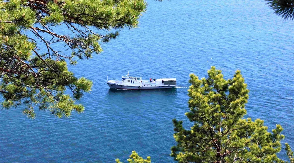 A boat cruising on the blue waters of Lake Baikal during a summer tour in Listvyanka