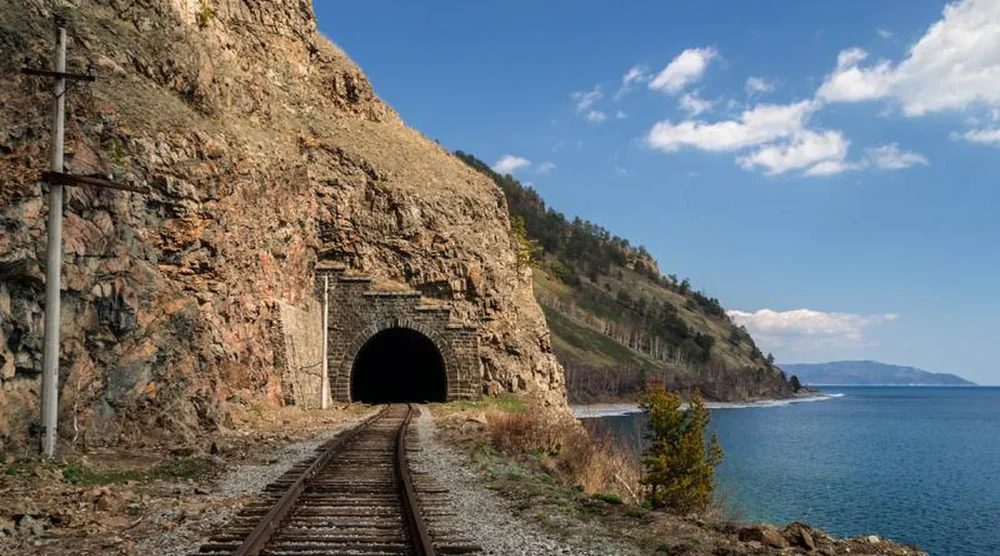 Railway track leading into a stone tunnel of the Circum-Baikal Railway along the shore of Lake Baikal