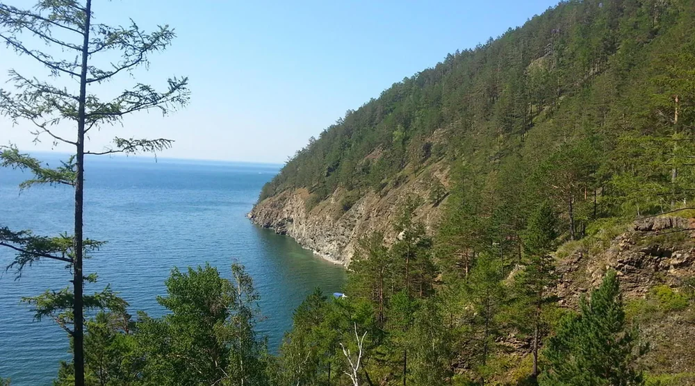 Scenic view of Lake Baikal shoreline with forested mountains and clear blue water near Listvyanka